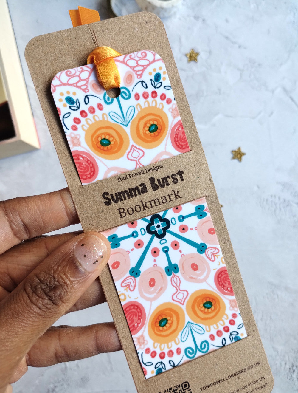 Close up of Summa Burst bookmark decorated with a sunset yellow ribbon in kraft recycled card packaging
