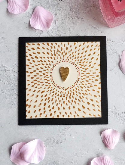 Love Shines Framed artwork with a heart design on a textured surface surrounded by pink petals.