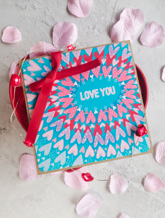 Teal Love radiating hearts greeting card with a hand tied red ribbon