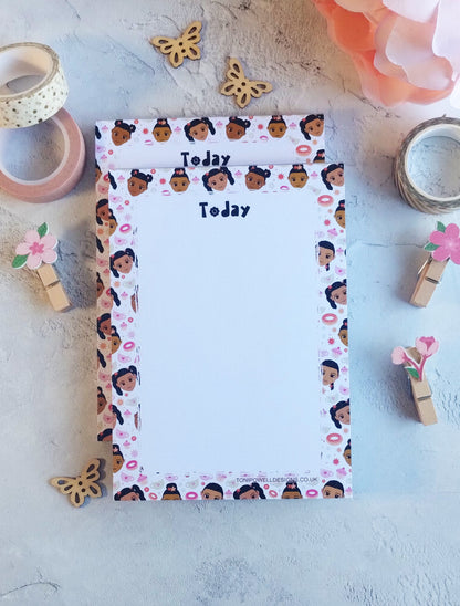 Notepad with a cute faces and sweet treats border on a concrete surface with decorative items.