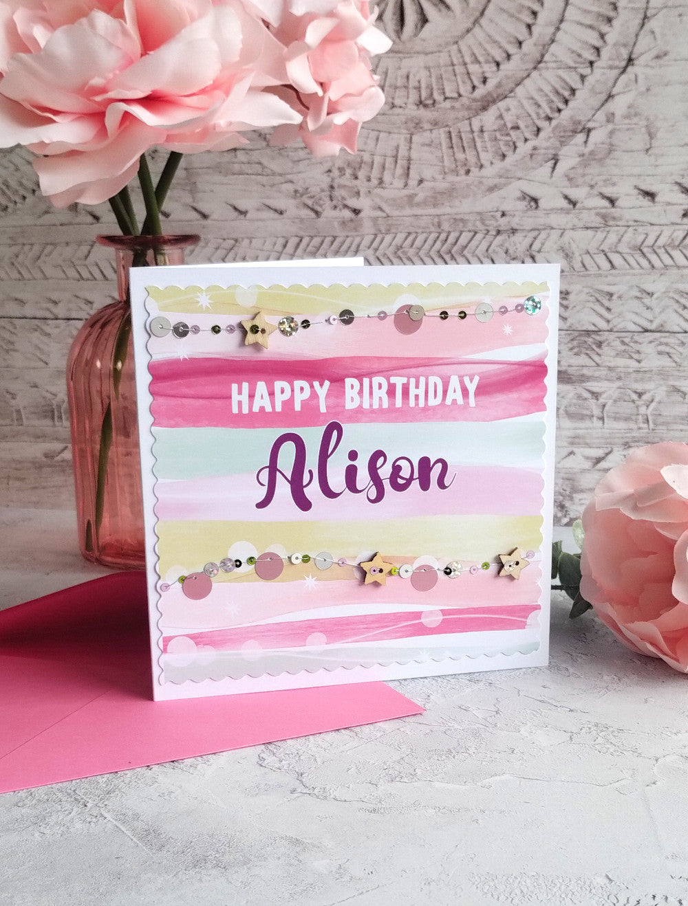 Personalised colourful birthday card with handsewn sequins and wooden stars with pink vase with flowers in the background