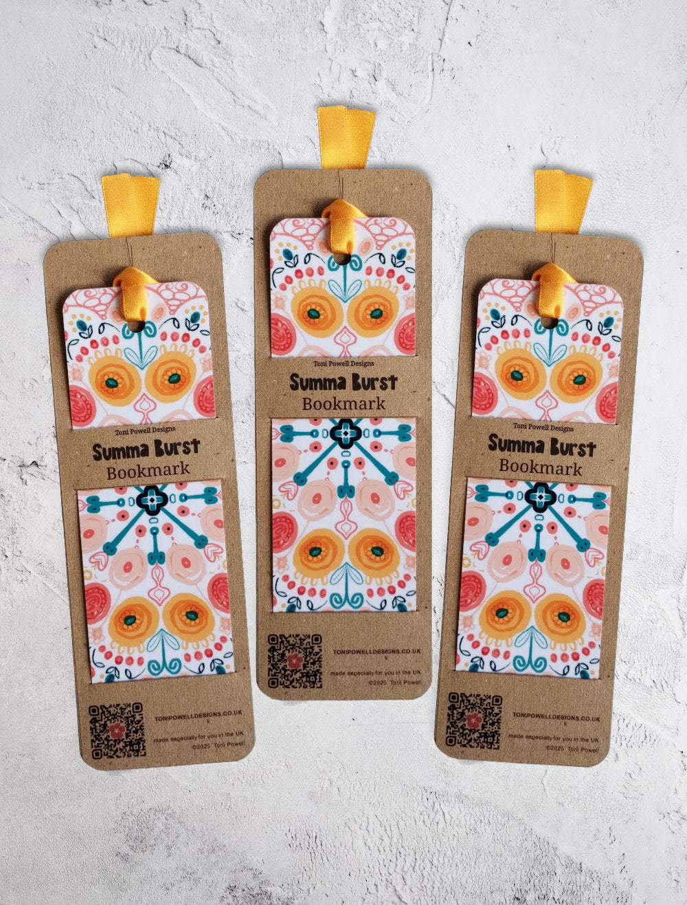 Summa Burst brightly patterned set of three bookmarks, embellished with a sunset yellow ribbon, in packaging