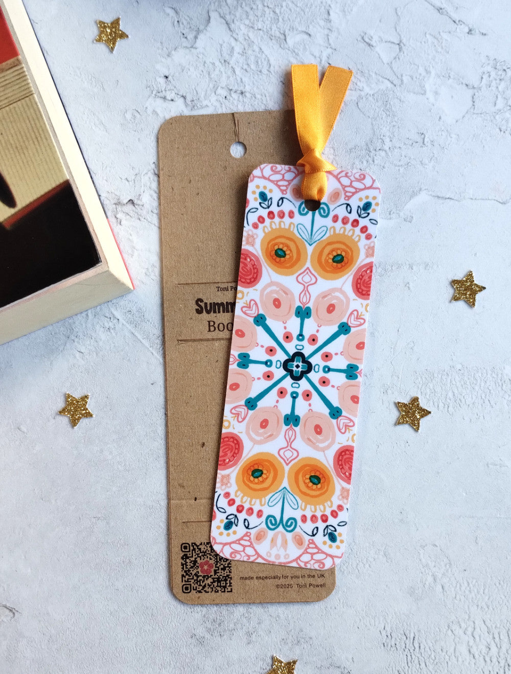 Summa Burst brightly patterned bookmark, embellished with a sunset yellow ribbon, outside of packaging