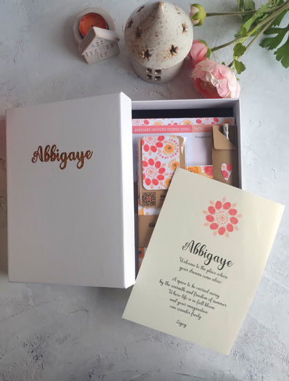 Open giftbox of handmade colourful stationery items including notebook, planner pad, note pad, pencil, magnetic bookmark and a gift box.