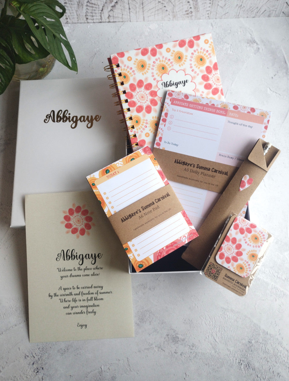 Colourful collection of handmade stationery items including notebook, planner pad, note pad, pencil, magnetic bookmark and a gift box.