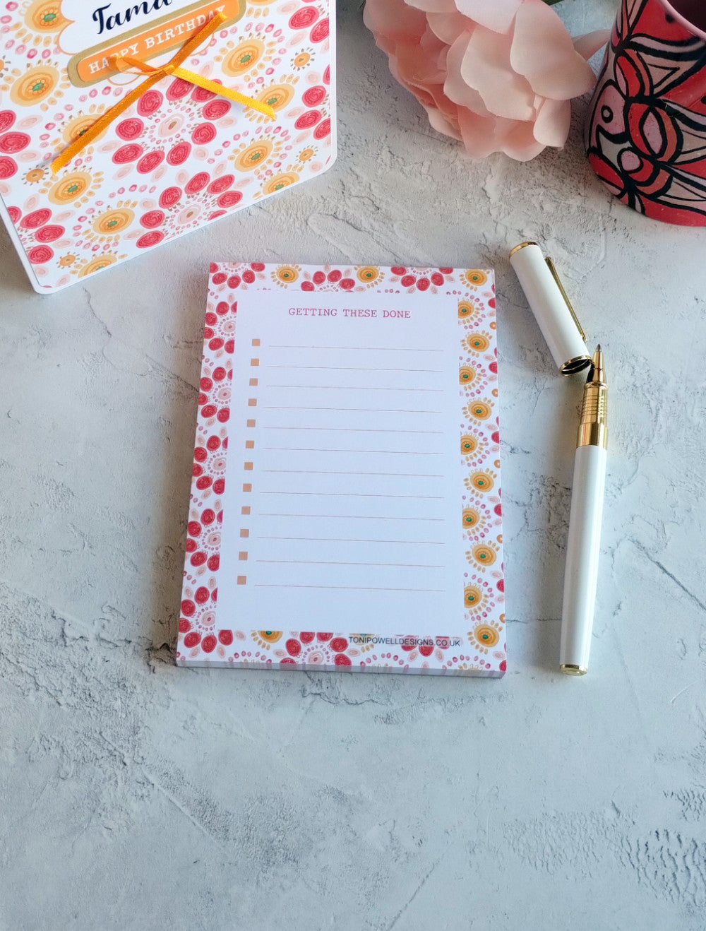 Bright pattern notepad with pen and matching card on a light surface