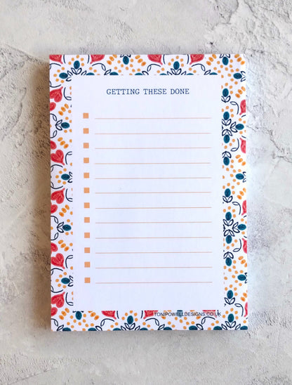 Notepad with a heart pattern border and text on a textured surface